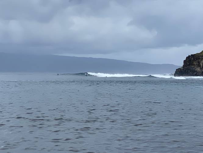 Surfers catching a wave at Honolua Bay