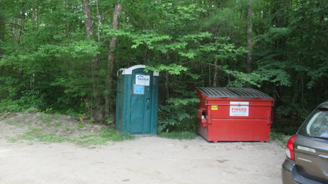 Port-a-potty and trash bin at Trailhead parking