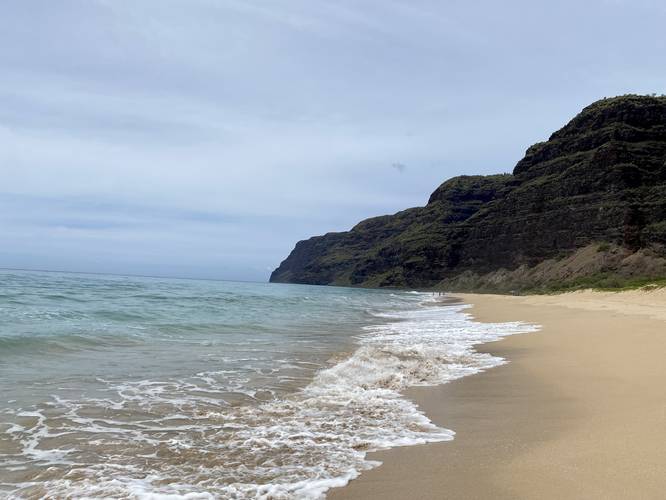 Ocean waves crash ashore at Polihale Beach, Polihale State Park with views of the southern end of the Na Pali coastal cliffs