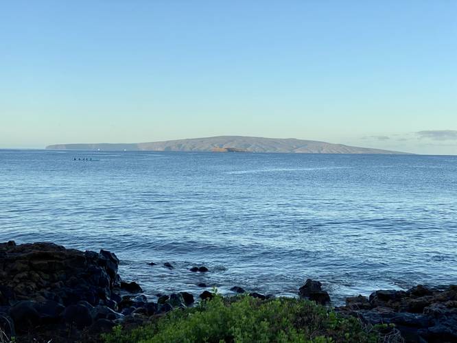 View of Molokini Crater and the island of Kaho'olawe from the Wailea Beach Path at sunrise with rowers in the ocean